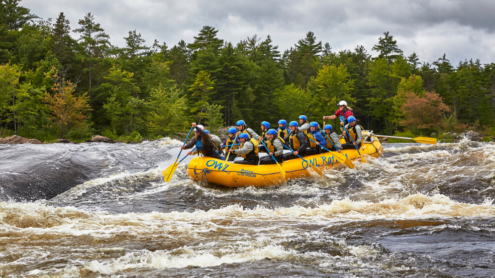 A yellow raft full of paddlers going through rapids on the Ottawa River.