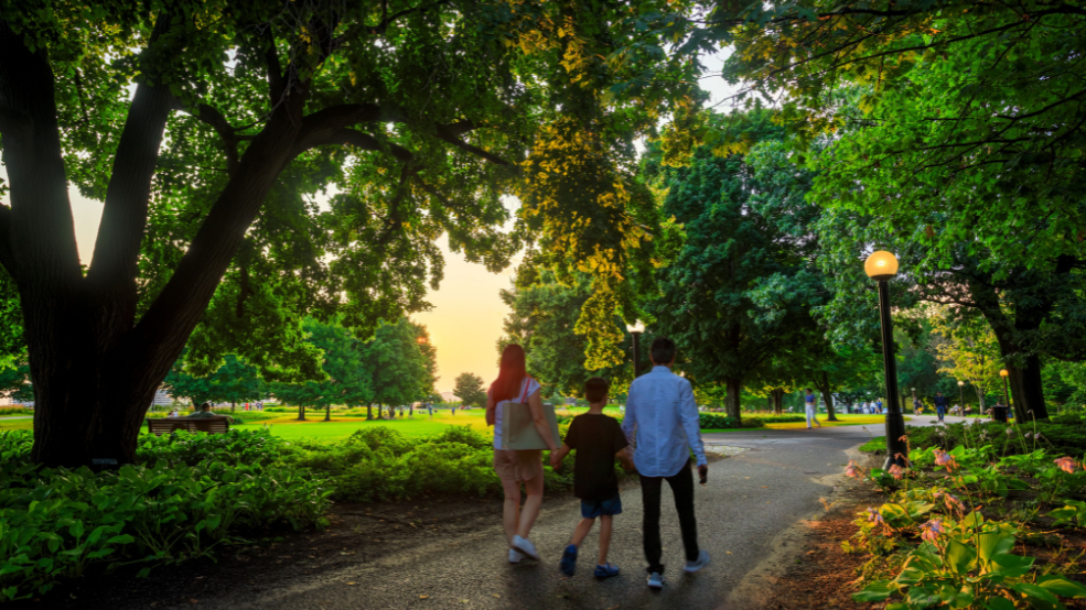 Parents and a child holding hands and walking along a path
