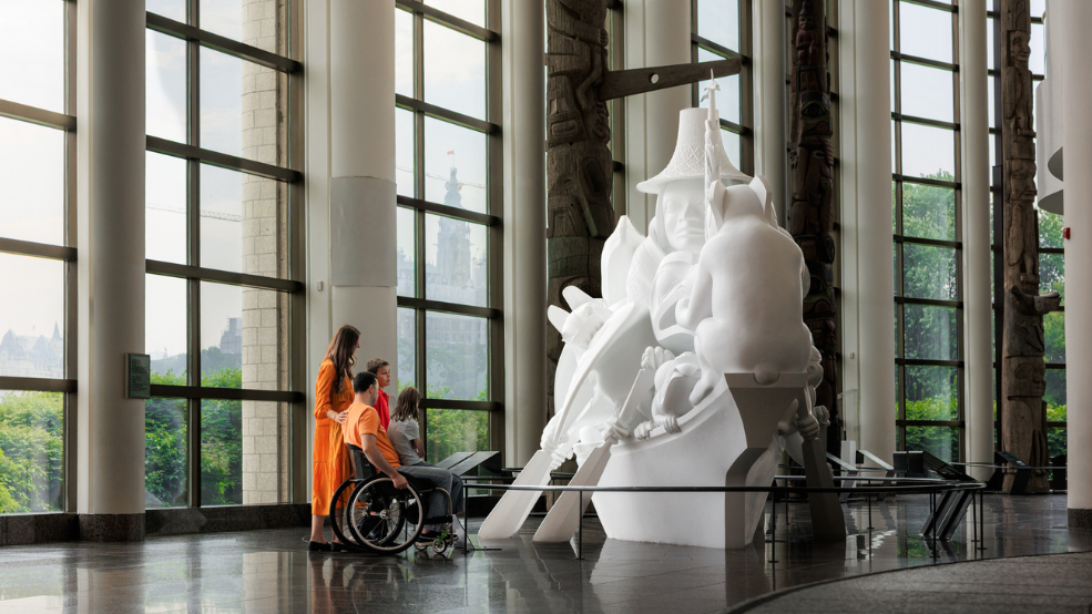 A family (including one wheelchair user) look at a sculpture at the Canadian Museum of History in Ottawa, Canada.