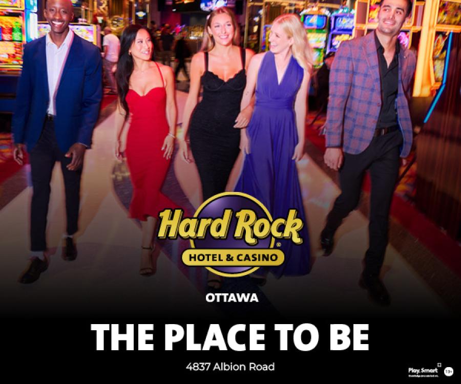A group of people walking together inside Hard Rock Hotel & Casino Ottawa, with colourful casino lights in the background. Overlaid text reads “Hard Rock Hotel & Casino Ottawa – The Place to Be.”