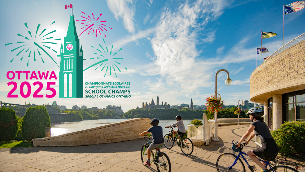 Family on bikes look at Parliament Hill with Special Olympics Ontario School Championships logo