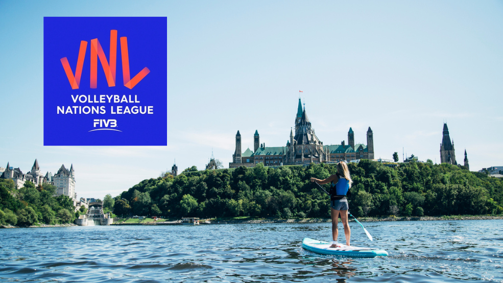 Person paddleboards on Ottawa River besides Parliament buildings