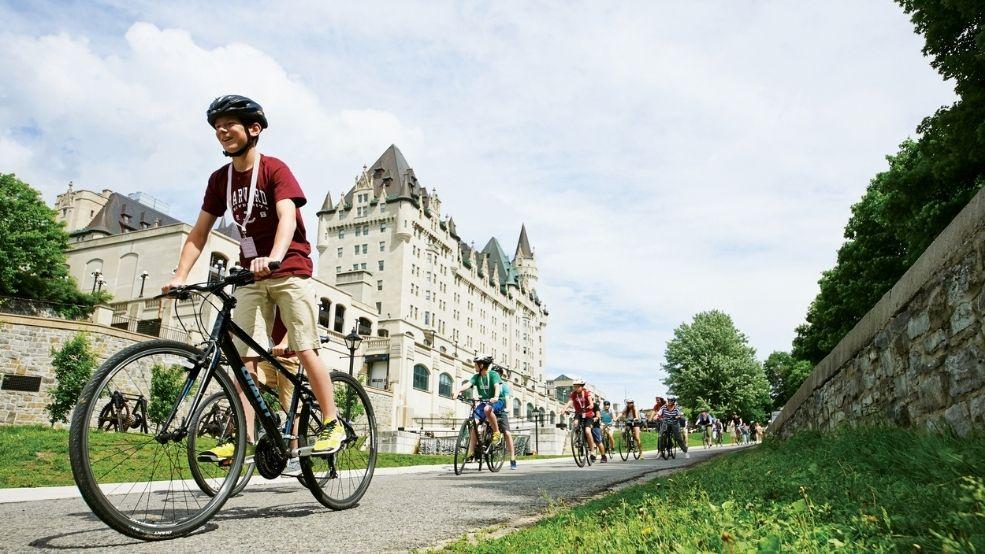 Students cycling beside the Rideau Canal with the Fairmont Château Laurier in the background