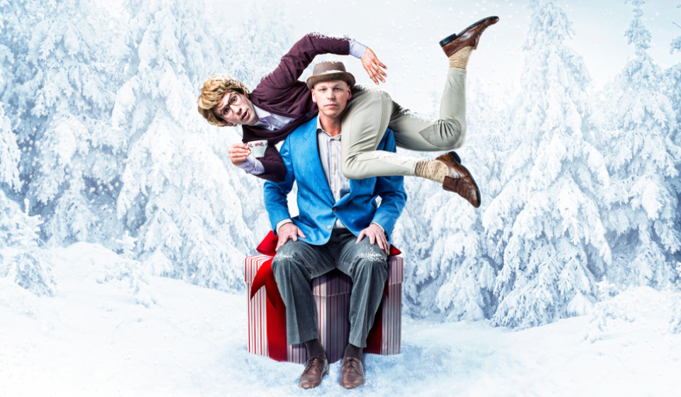 Performers Aaron Malkin and Alastair Knowles pose comedically in a promotional photo of their production O Christmas Tea. In the background there is snow and trees in a winter wonderland themed backdrop.