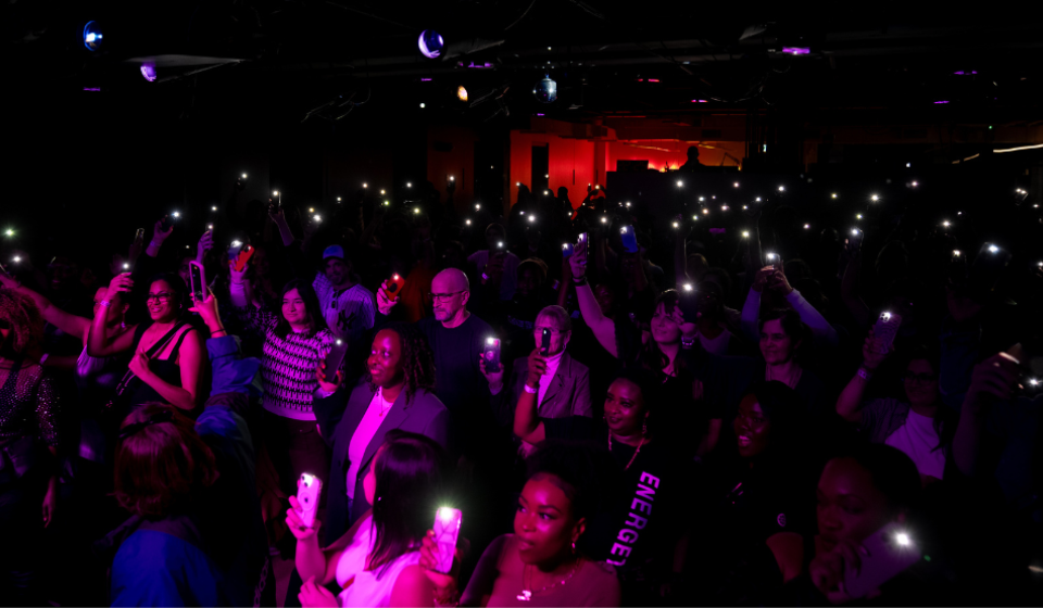 Crowd of people in a dark room with their phone's flashlight on