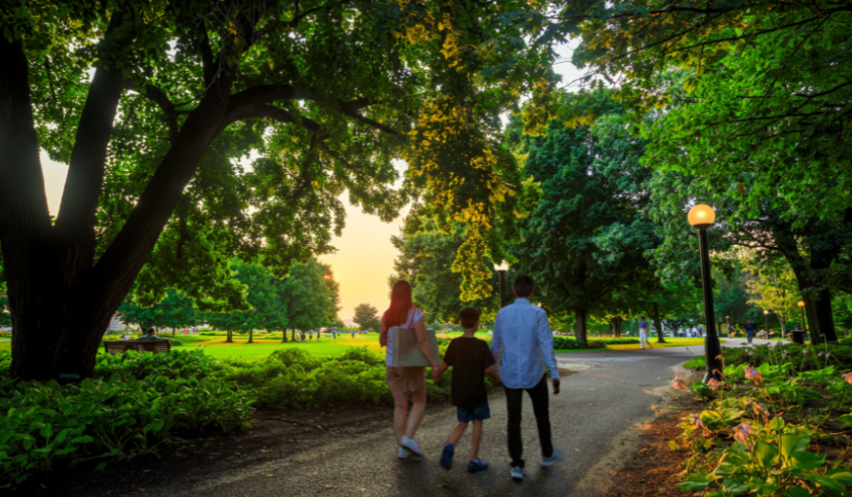 Parents and a child holding hands and walking along a path