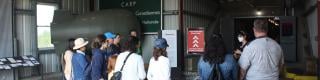 A group of visitors stand in a group in front of a museum tour guide at the entrance to the Diefenbunker.