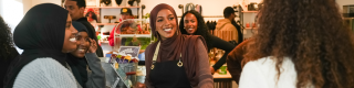 A woman smiles at customers from behind the counter of a cafe.