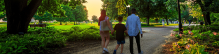 Parents and a child holding hands and walking along a path