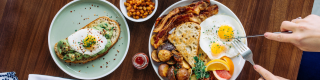 A wooden table set for two with breakfast dishes and coffee